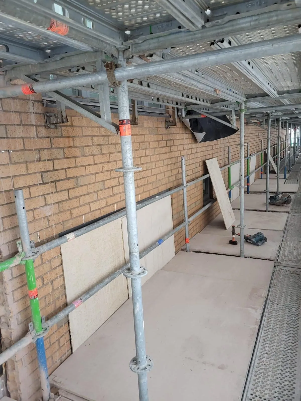 Newly rebuilt buff facing brickwork elevation seen from the scaffold, laid level and to line