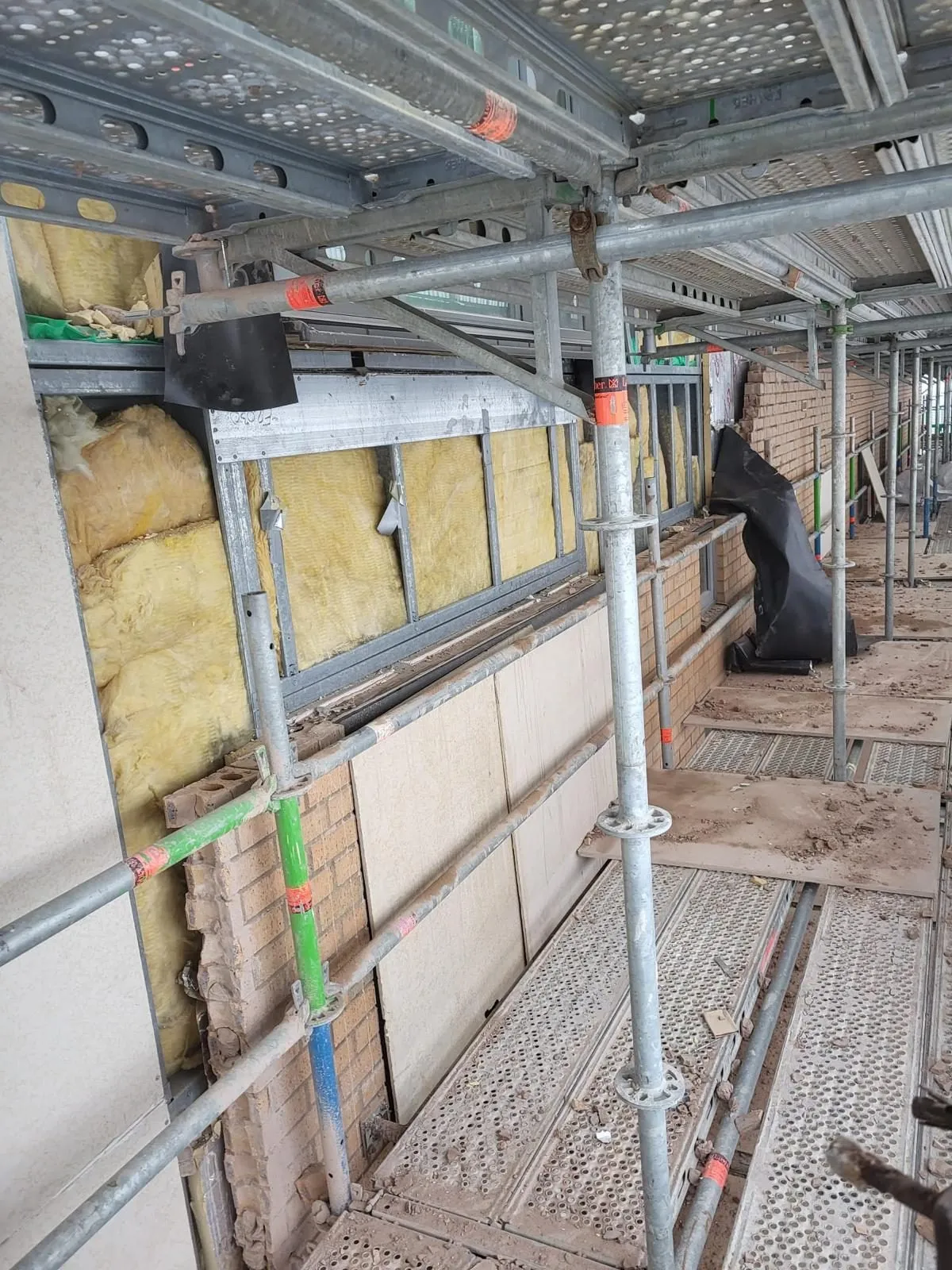 Exposed light gauge steel frame with mineral wool insulation between studs on a stripped building facade